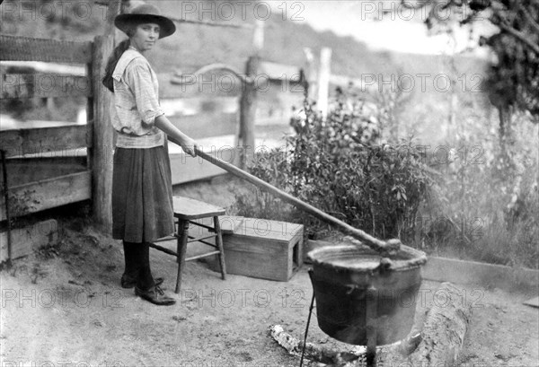 Little Orleans, Maryland:  October 28, 1920.
A young girl making apple butter the same way her great great grandparents made it years ago. She is using the same iron pot and stirring stick that has been used for years. it is easy to make, and only requires five hours of constant stirring.