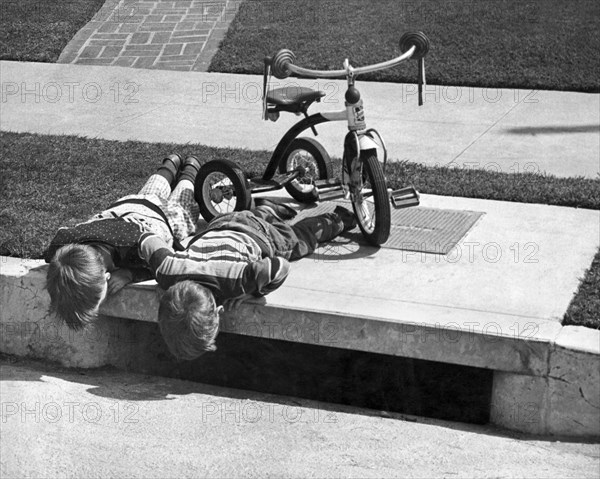 Two Boys Peer In Storm Drain