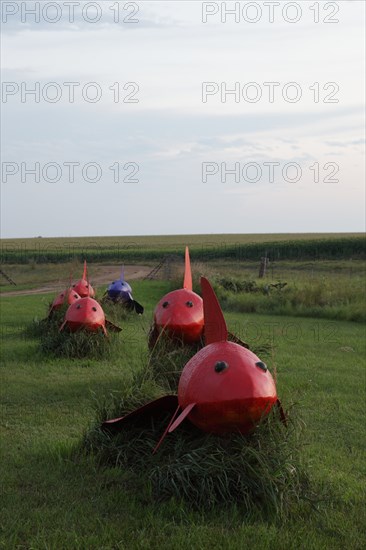 Weird red bugs with shark like appearance march across the plain; Located just off Interstate 90 in the South Dakota Drift Prairie, about 25 miles west of Sioux Falls. Many of the sculptures, in the style of industrial art, were made with scrap metal, old farm equipment, or railroad tie plates. 2006