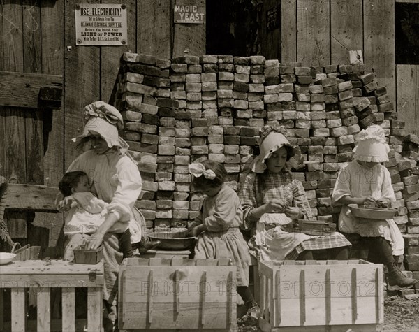 A mother hulling berries while she nurses her infant.  1911