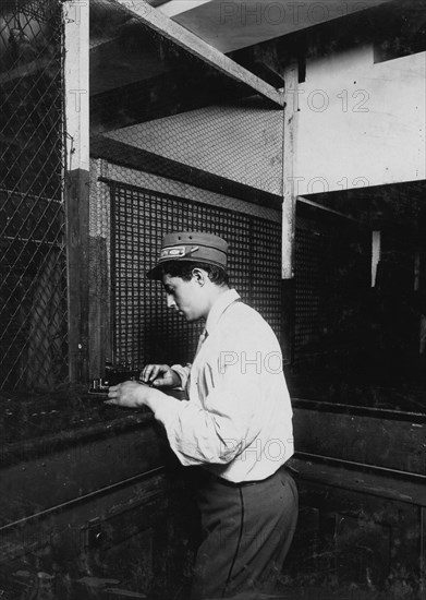 A Postal Telegraph boy learning to send messages during spare moments. 1910