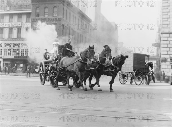 Team of Horses pulls a steam pumper across paved streets toward a fire scene.