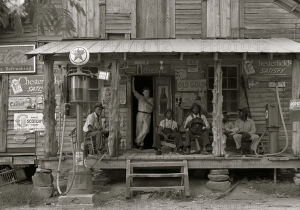 African American and a white store owner on the Porch of a country store 1939