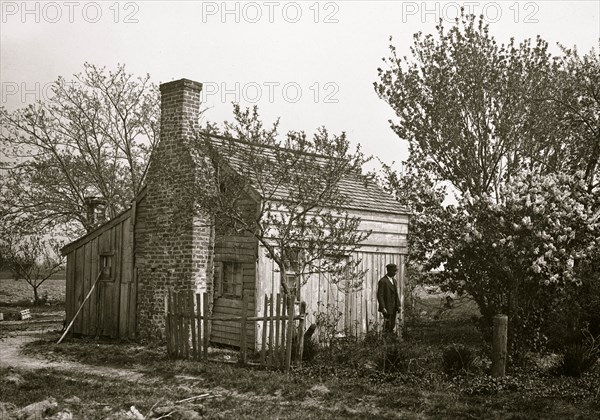 African American man in front of small house 1901