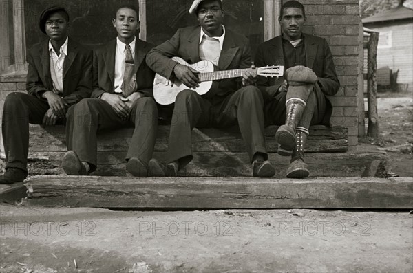 African American on bench while one plays the guitar 1935