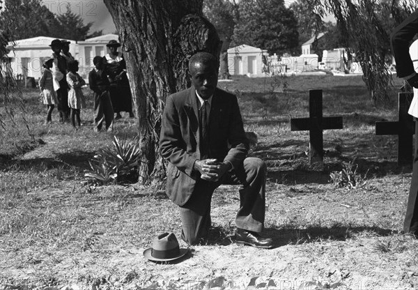 Black crossing himself and praying over grave of relative in cemetery, All Saints' Day, New Roads, Louisiana 1938