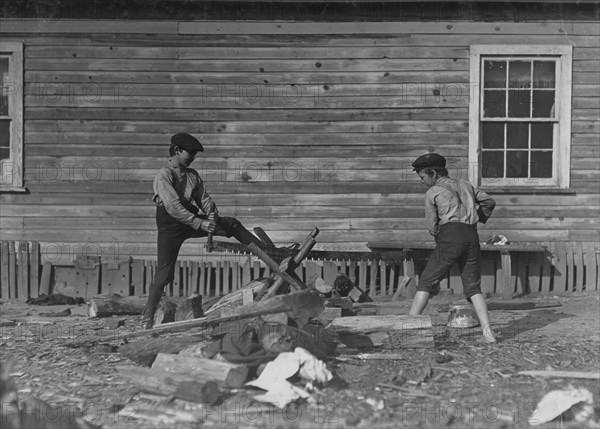 Two young boys from the Cotton Mill use a large crosscut saw 1908