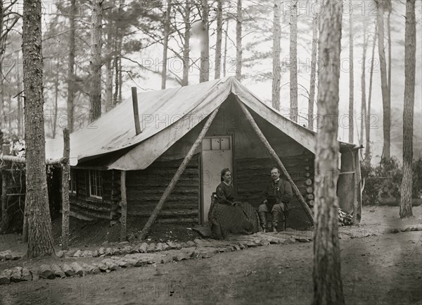 Brandy Station, Virginia. Col. John R. Coxe, A.C.S., and lady seated before his log-cabin winter quarters at Army of the Potomac headquarters 1864