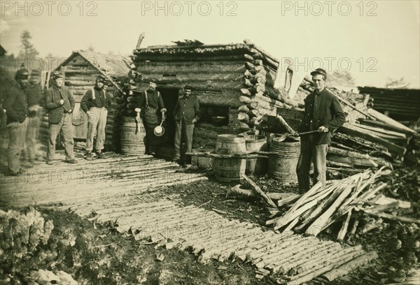Civil War camp of the 6th N.Y. Artillery at Brandy Station, Virginia, showing Union soldiers in front of log company kitchen 1864