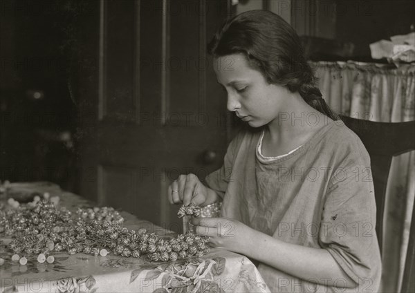 Cottage Industry shows young girl stringing material in piecework done at home. 1924