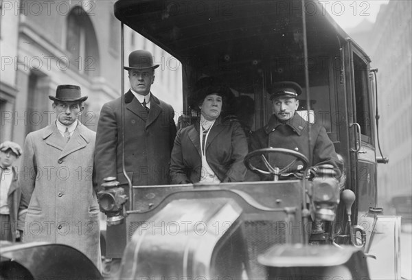 Four dour people, one of whom is their driver look posed while seated in their taxi