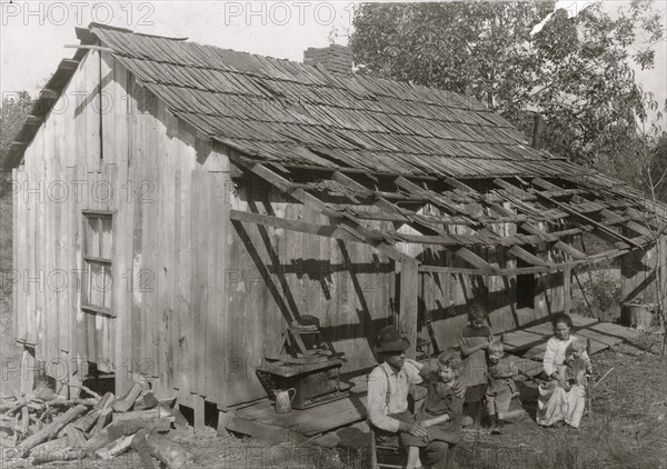 Frank Burditt and family. They rent this dilapidated shack and are trying to make a living off the meager land near by.  1921