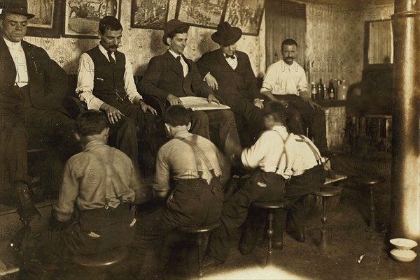 Greek Bootblacks are lined up along a shoeshine stand polishing client's shoes 1908