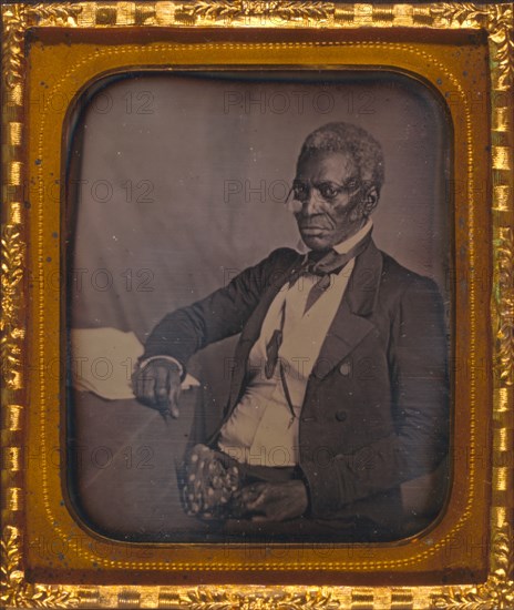 John Hanson, three-quarter length portrait, three-quarters view, wearing glasses, seated at desk 1857