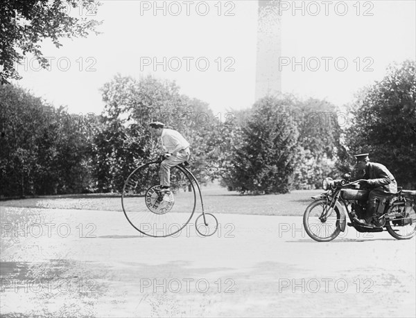 Motorcycle cop chases a Penny Farthing Velocipede down a DC Street with Washington Monument in background 1921