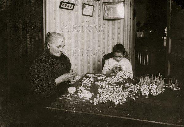 Mrs. Monte Mora, Fifty-five years old, is janitress for a large tenement, 133 W. Houston St., (lives Apt. 7) housing 26 families. When not tending the furnace or occupied with other duties for others and her own family, she makes flowers, assisted by her niece Josephine,  1912