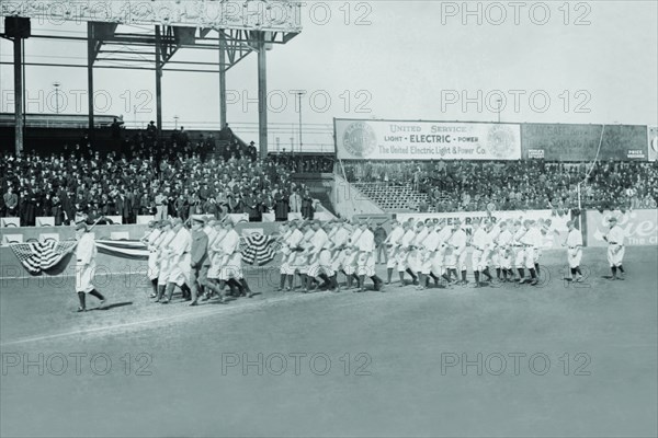 New York Yankees show support for the Troops in World War I by marching around the stadium on baseball uniforms and carrying rifles over their shoulders. 1917