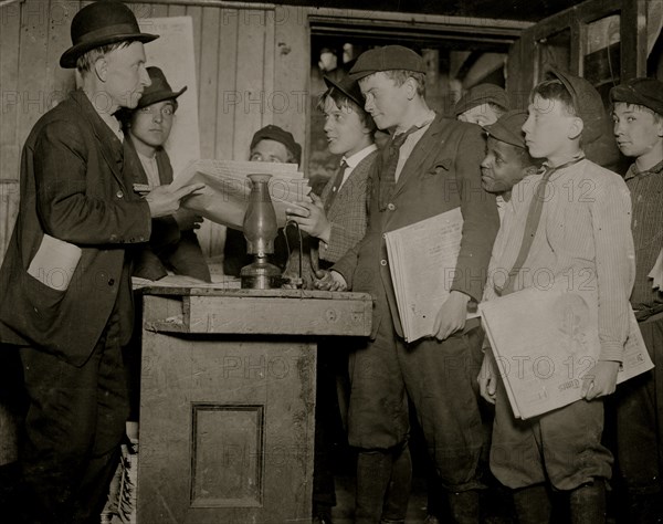 Newsboys pick up their papers and settle up in a basement Branch or office for newspaper sales 1910