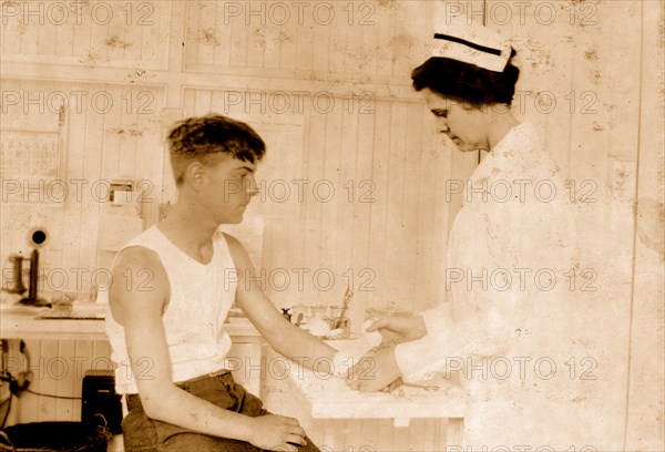 Nurse at Cheney Silk Mills bandages a boy's arm 1924