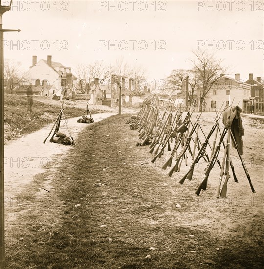 Petersburg, Va. Row of stacked Federal rifles; houses beyond 1865