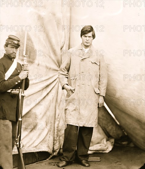 Washington Navy Yard, District of Columbia. Lewis Payne, standing in overcoat and without hat. Federal guard standing on left 1865