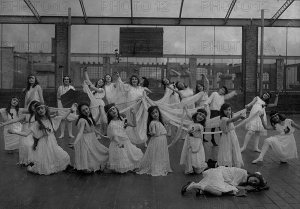 The dance of the Children of the Sunshine with Ellen sleeping in the foreground. Miss Mackay's Pageant Children of Sunshine and Shadow as presented at Washington Irving High School. 1916