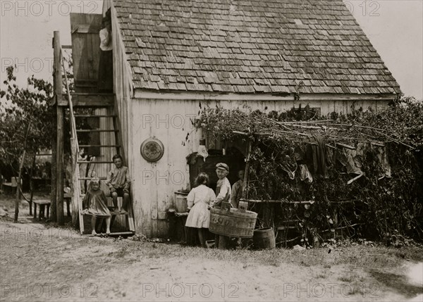 Three families is the rule in these shacks, one room above and one below, but sometimes four families crowd in. 1910