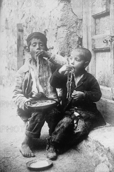 Two Neapolitan Children slurp down Spaghetti