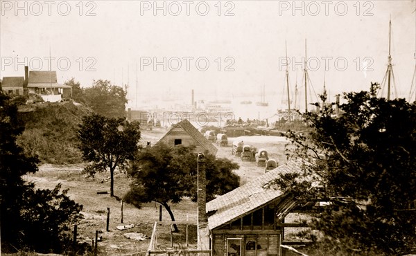 View of City Point, Virginia, with covered wagons moving toward pier and harbor in background 1864