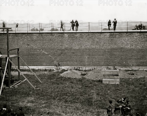 Washington, D.C. Coffins and open graves ready for the conspirators' bodies at right of scaffold 1865