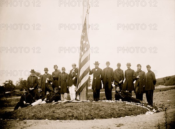 Washington, D.C. Signal Corps officers lowering flag at their camp near Georgetown; Gen Albert J. Myer, in civilian dress, at right of pole 1865