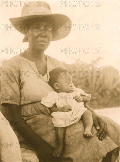Woman sitting and holding infant, Cat Island, Bahamas 1935