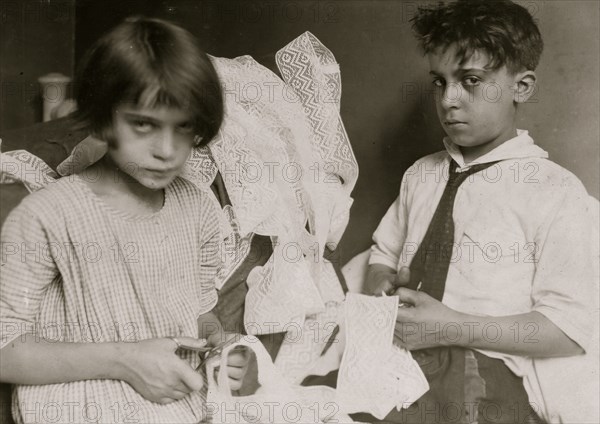 Young boy and young girl cutting fabric in work taken in at home in their tenement 1924