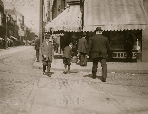 Young boy peddles out of a basket 1909