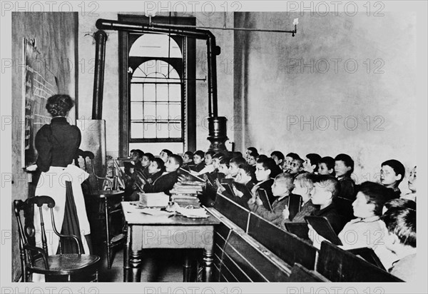 Teacher Instructs Students from Blackboard in Classroom 1890