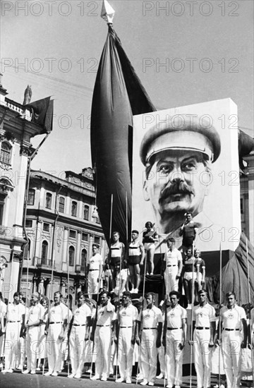 Participants in the annual physiacal culture parade standing under a portrait of joseph stalin near red square in moscow, ussr, 1930s.