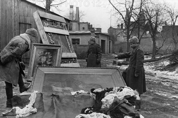 Red army soldiers with recovered paintings stolen from the peterhof palace (petrodvorets) and pushkin palace (tsarskoye selo) by the germans, abandoned in east prussia during the nazi retreat, world war 2, 1945.