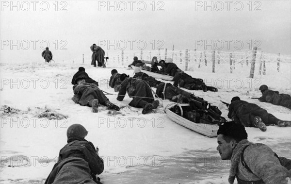 Red army troops move past frosty barbed wire dragging sleds with machine-guns on the leningrad front.