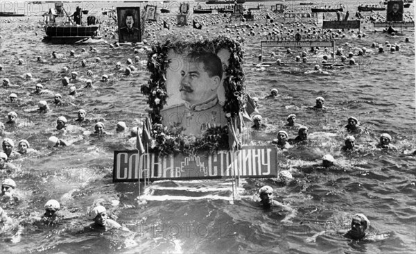 Soviet sailors swimming with floats with portraits of stalin in celebration of ussr navy day, sevastopol, ussr, july, 1950.