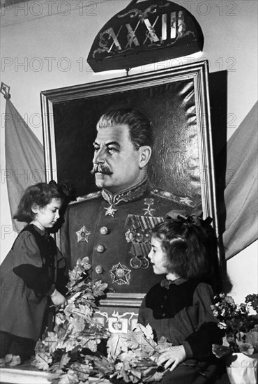 Two young girls at a kindergarten in the sverdlov district of moscow adorning a portrait of joseph stalin with greenery on the eve of the 33rd anniversary of the great october socialist revolution, november 7,1950.
