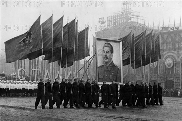 A demonstration / parade of the working people in red square in moscow on november 7, 1950, the sportsmen are carrying soviet flags and an image of stalin.