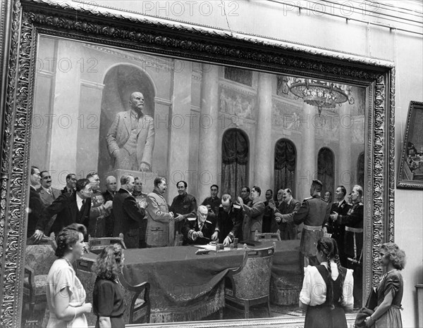 Visitors examining the painting 'in the name of peace' by soviet artists v, vikhtinsky, b, zhukov, e, levin, l, chernov, and l, shmatkov at the exhibition of ukrainian fine arts in the tretyakov gallery in moscow, july 1951.
