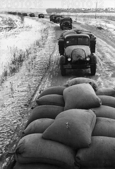 Trucks delivering grain to the state granary, 1965, over 30 state farms under the northeast land reclamation bureau in heilungkiang province registered a big increase in staple agricultural produce in 1964 and sold 20% more grain to the state the same year.