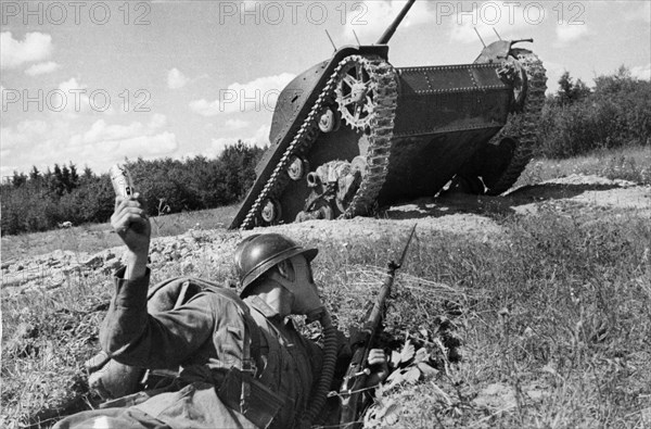 Soviet infantry man in a gas mask preparing to throw a grenade at a tank during training exercises, 1940.