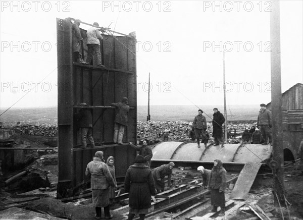 Post-war donbass heals it's wounds, setting up a cylindrical head-frame, designed by engineer zherbin, at the dzerzhinsky colliery no, 12 in donbass, ussr, 1940s.