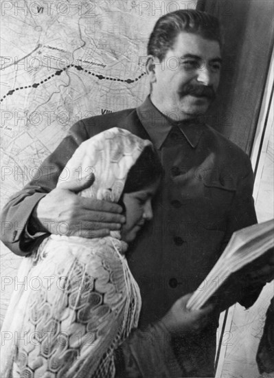 Propaganda photo of josef stalin as benevolent father figure with eleven year old mamlakat nakhangova, a schoolgirl from the lakhuti collective farm, stalinabad region, tajikistan soviet republic, kremlin palace, moscow, ussr, december 1935.