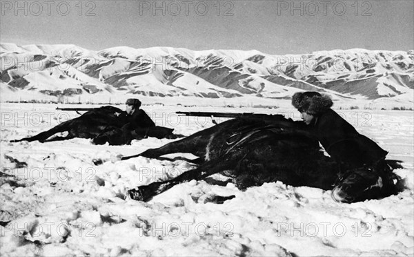 Training of red army reserves, the ossoaviakhim riding club of the kirghiz soviet socialist republic is training youths of call age and men undergoing universal military training, trainees firing from behind horses, march 1942.