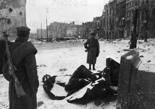 world war ll, polish soldiers standing by the toppled sigismund lli column (sigmund column) in castle square in warsaw during the first days of it's liberation.