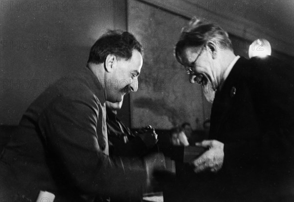 M, i, kalinin, president of the central executive committee of the ussr, awarding the order of the red banner of labor to grigoriy konstantinovich ordzhonikidze (sergo ordzhonikidze), the people's commissar of heavy industry, for over-fulfilling the production plan of 1935.