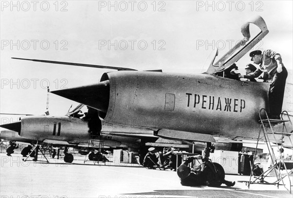 September 1966: a north vietnamese student pilot in a non-flying mig-21 fighter jet trainer, with him is his soviet flight instructor, lettering on fusilage: 'trainer'.